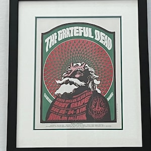 Pode incluir: Um cartaz de concerto vintage para The Grateful Dead com um esquema de cores vermelho, branco e verde. O cartaz apresenta uma ilustração de desenho animado de um homem com barba e chifres. O texto no cartaz diz "The Grateful Dead", "Moby Grape", "Steve Miller Blues Band", "Avalon Ballroom", "Dec 23-24-9 PM", e "Concert Dance".