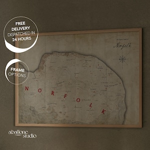 May include: A vintage-style map of Norfolk, England, printed on aged paper and framed in a light wood frame. The map shows the county's coastline, rivers, and towns. The title "The English County of Norfolk" is written in cursive at the top of the map.