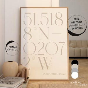 May include: A beige framed print with the coordinates 51.518 8°N-0.207 2°W and the text "PORTOBELLO ROAD". The print is displayed on a wall with a beige sofa in the background.