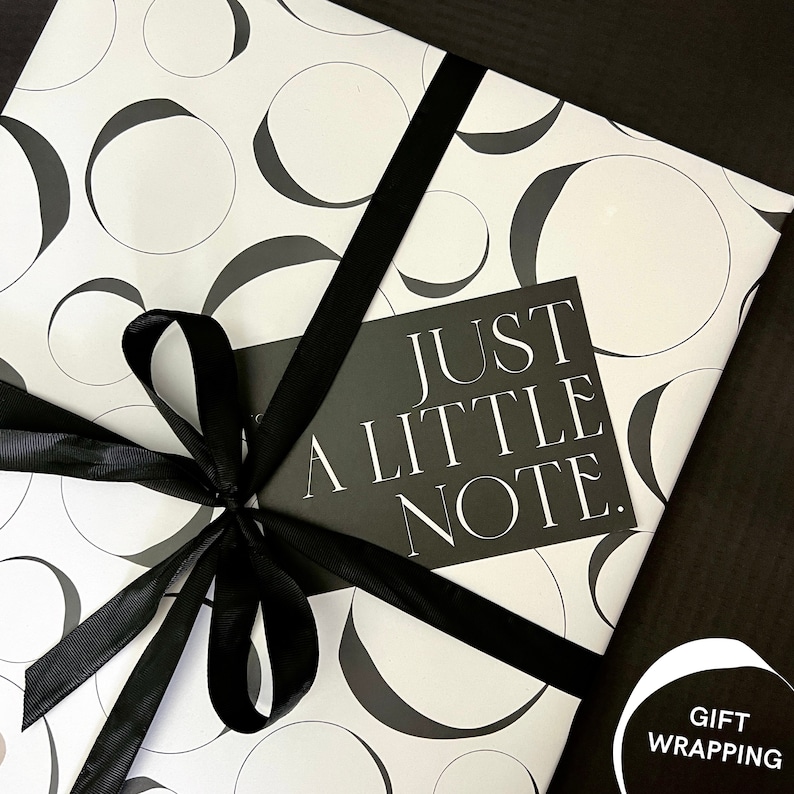Peut inclure: Papier d'emballage cadeau noir et blanc avec un ruban noir et une carte qui dit "Just a little note."
