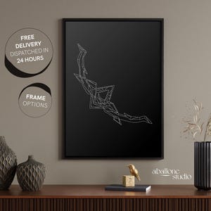May include: A black and white geometric design of a bow and arrow on a black background. The design is framed in a black frame and is hanging on a wall.