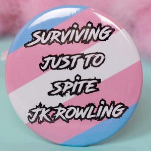 May include: A white ceramic mug with a black handle and the text "But First, Coffee" in a bold, black font. The mug is set against a blurred background. The mug appears to be approximately 10 cm tall.