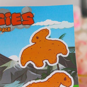 May include: A sticker sheet with a cartoon illustration of a chicken nugget shaped like a dinosaur. The sticker sheet has the text "NUGGIES" and "STICKER PACK" on it.