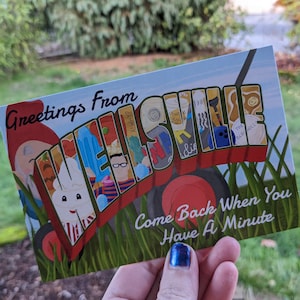 May include: Greetings from Wellsville postcard with a red, white, and blue illustration of the town name. The postcard features a variety of small illustrations, including a gnome, a hot dog, a person with glasses, and a bowling ball. The text "Come Back When You Have A Minute" is printed on the bottom of the postcard.