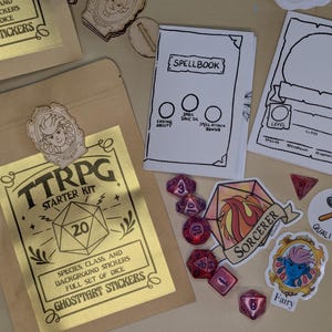 May include: A TTRPG Starter Kit with dice, stickers, and a spellbook. The kit includes a gold foil bag with the text "TTRPG Starter Kit" and "Ghostart Stickers". Also included are dice, stickers, and a spellbook.