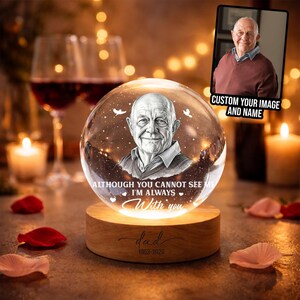 Könnte beinhalten: Personalisierte Gedenk-Kristallkugel mit einem Porträt eines Mannes, auf einem Holzsockel. Die Kugel trägt den Text "ALTHOUGH YOU CANNOT SEE ME I'M ALWAYS With you" und "dad 1953-2026". Ein Foto wird in der Ecke angezeigt.
