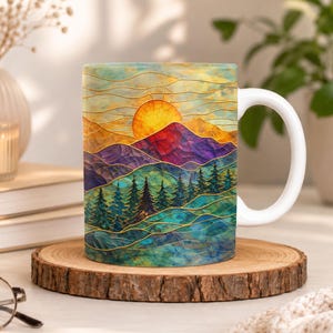 May include: A white ceramic mug featuring a vibrant, textured landscape illustration of a bright yellow sun setting behind purple and blue mountains, with a dense forest of dark green pine trees in the foreground and thin gold line accents.