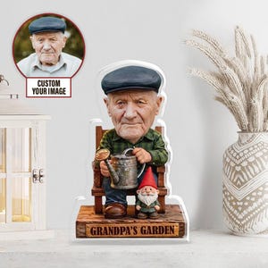 Könnte beinhalten: Personalisierte Gartendekoration aus Acryl mit einer Karikatur eines älteren Mannes in einem grünen karierten Hemd und einer blauen Mütze, der eine Gießkanne hält. Ein kleiner Gartenzwerg steht daneben. Die Basis lautet "Grandpa's Garden."
