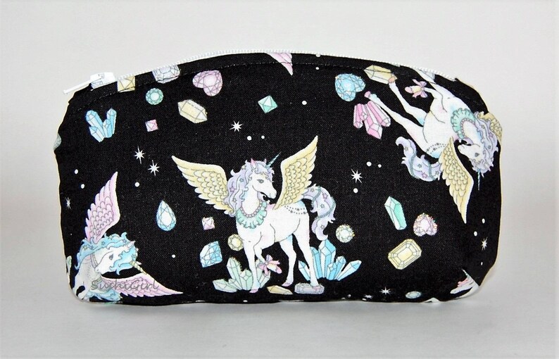 Puede incluir: Bolsa negra con cremallera con un dise&ntilde;o de unicornio y cristal. La bolsa presenta dos unicornios con alas y una variedad de cristales coloridos.