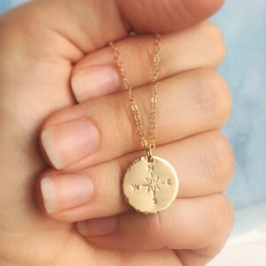 Puede incluir: Collar de oro con un colgante de br&uacute;jula. La br&uacute;jula tiene una estrella y las letras N, S, E y W.