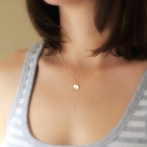 May include: A gold chain necklace with a small, round pendant. The pendant is smooth and has a subtle shine.