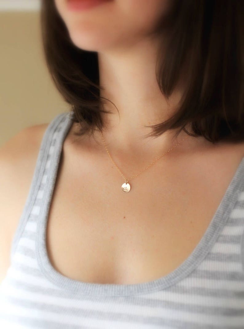 May include: A gold chain necklace with a small, round pendant. The pendant is smooth and has a subtle shine.