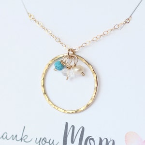May include: Gold necklace with a hammered circle pendant and three small beads: turquoise, white pearl, and clear quartz.
