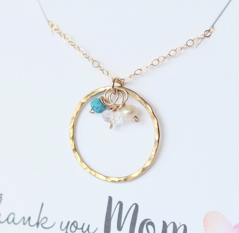 May include: Gold necklace with a hammered circle pendant and three small beads: turquoise, white pearl, and clear quartz.