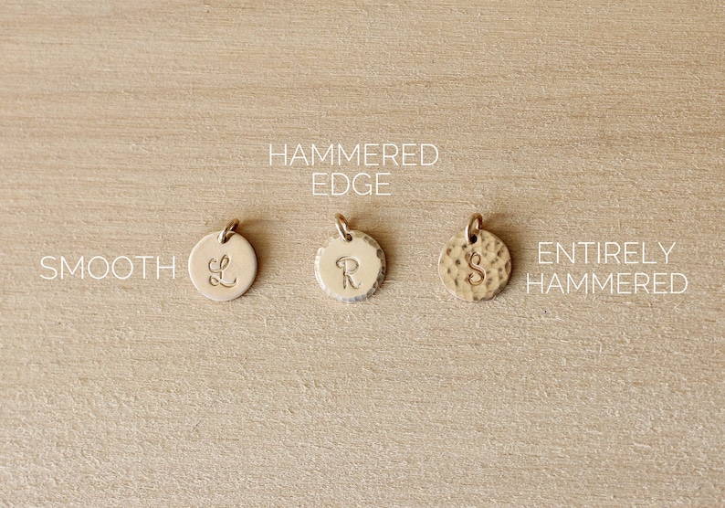 May include: Three gold-coloured metal discs with different finishes. The disc on the left is smooth, the middle disc has a hammered edge, and the disc on the right is entirely hammered. Each disc has a different letter engraved on it: L, R, and S.