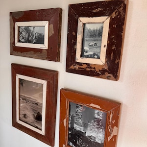 May include: Four rectangular picture frames with black and white photos. The frames are made of distressed wood with a reddish-brown and white color scheme. The photos depict various scenes.