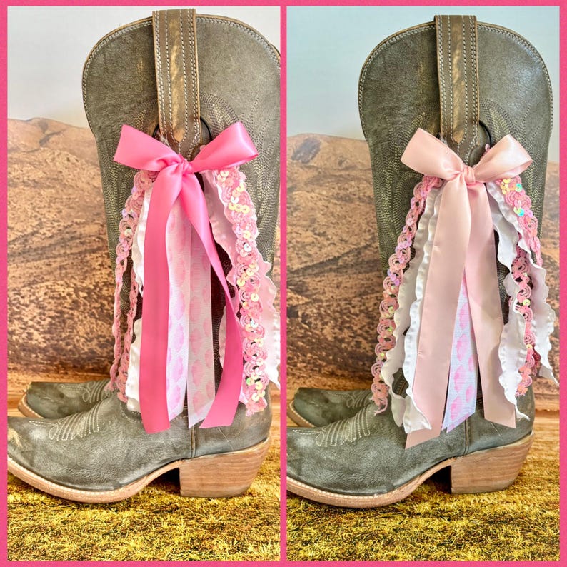 May include: Two gray leather cowboy boots, each adorned with a decorative ribbon tassel. The left boot features a bright pink satin bow with matching pink and white sequined ribbons. The right boot has a pale pink bow with similar sequined accents.