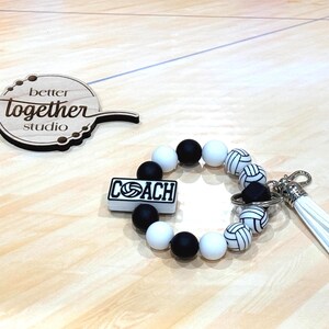 May include: Black and white volleyball themed keychain with a beaded bracelet and a charm that says "COACH".