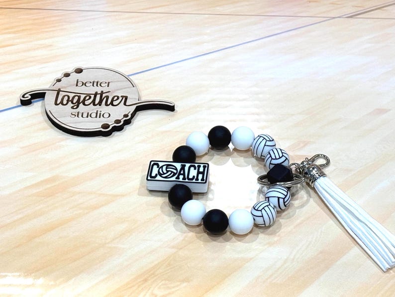 May include: Black and white volleyball themed keychain with a beaded bracelet and a charm that says "COACH".