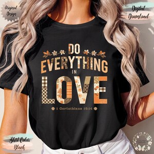 May include: Black t-shirt with the text "DO EVERYTHING IN LOVE" in a patchwork design with floral and plaid patterns. The shirt also includes the Bible verse "1 Corinthians 13:14". The design has orange, brown, and white colors.