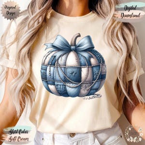 May include: A soft cream t-shirt with a blue and white patchwork pumpkin design, a blue bow, and pearl accents. The words "Original Design" and "Digital Download" are visible.