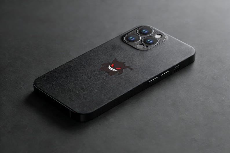 K&ouml;nnte beinhalten: Schwarze Smartphone-H&uuml;lle mit einem Gengar-Motiv. Die H&uuml;lle hat eine matte Oberfl&auml;che und zeigt ein stilisiertes Bild von Gengar mit rotem Mund und Augen. Die Kameralinsen des Telefons sind oben sichtbar.