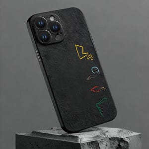 Può includere: Custodia per telefono nera con superficie strutturata e grafica a linee colorate. Il design include un fulmine giallo, una 'C' blu, una forma rossa e una forma verde. La custodia è esposta su un blocco grigio scuro.