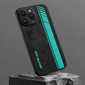 Op de afbeelding: Zwarte telefoonhoes met een getextureerde afwerking en een turquoise streepontwerp. De hoes heeft het AMG-logo in turquoise. De telefoonhoes wordt gepresenteerd op een stenen blok tegen een grijze achtergrond.