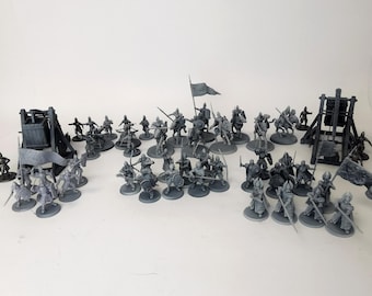 Könnte beinhalten: Eine Sammlung grauer Miniaturfiguren, die eine mittelalterliche Kampfszene darstellen. Das Set umfasst Soldaten zu Fuß und zu Pferd, Belagerungswaffen und Banner, alles auf einer weißen Oberfläche angeordnet.
