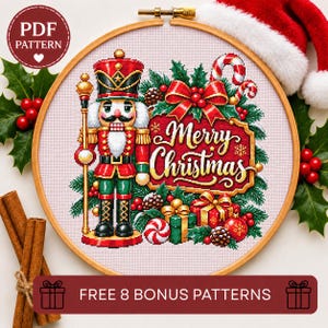 May include: A cross-stitch pattern in a wooden embroidery hoop featuring a nutcracker, a red sign with the text Merry Christmas in gold script, wrapped gifts, holly, and a candy cane. The design is on white fabric with a red and white border.