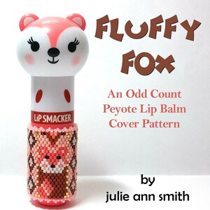 May include: A pink and brown beaded cover for a Lip Smacker lip balm tube. The cover features a fox design and the text "FLUFFY FOX An Odd Count Peyote Lip Balm Cover Pattern by julie ann smith".