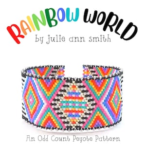 Puede incluir: Una pulsera de puño ancha y abierta con un patrón geométrico en colores vibrantes. La pulsera presenta un diseño de diamante central en rosa, naranja, azul y verde, bordeado por rayas blancas y negras. El texto en la parte superior dice "Rainbow World" y "by julie ann smith."