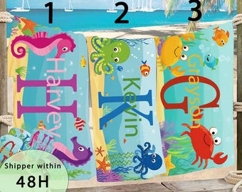 May include: Three personalized beach towels with aquatic designs. Each towel features a name: "Harvey", "Kevin", and "Grayson", with colorful sea creatures like seahorses, octopuses, and crabs. The background shows a beach scene with the text "Shipper within 48H Made in US".