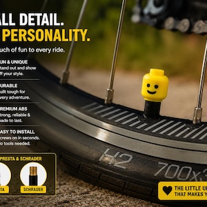 May include: A bright yellow toy-style head valve cap with a black smiling face graphic attached to a bicycle tire valve. The image includes text: SMALL DETAIL. BIG PERSONALITY. Add a touch of fun to every ride. FITS PRESTA & SCHRADER.