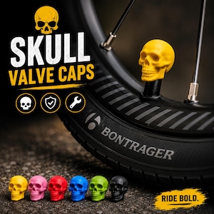 Könnte beinhalten: Ein Set aus totenkopfförmigen Ventilkappen in Gelb, Pink, Rot, Blau, Grün und Schwarz. Eine gelbe Totenkopf-Ventilkappe ist an einer schwarzen Fahrradfelge befestigt. Der Text SKULL VALVE CAPS und RIDE BOLD. ist zusammen mit Totenkopf-, Schild- und Schraubenschlüsselsymbolen zu sehen.