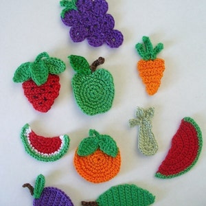May include: Crocheted fruit and vegetable shapes in various colors, including green, red, orange, purple, and white. The shapes include a grape bunch, strawberry, apple, carrot, watermelon slice, orange, plum, and a green leaf.