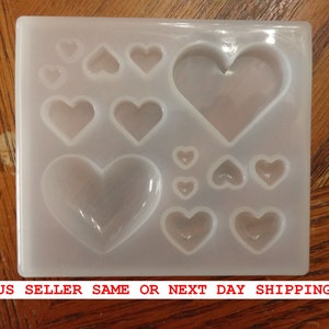 May include: A white silicone mold with 10 heart-shaped cavities of varying sizes. The mold is designed for making resin crafts.