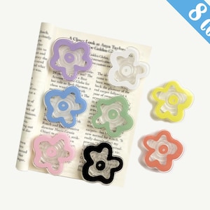 May include: Eight colourful flower-shaped clips with a clear centre. The clips are made of plastic and have a glossy finish.