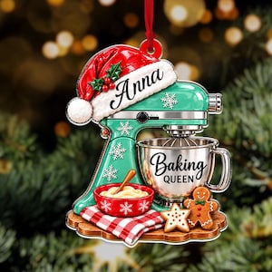 May include: A mint green stand mixer Christmas ornament featuring a red Santa hat with the name Anna, a silver mixing bowl labeled Baking Queen, a red bowl with dough, a red and white checkered cloth, a star cookie, and a gingerbread man.