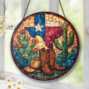 Könnte beinhalten: Runde Glasmalerei mit dem Texas-Bundesstaatflagge, Cowboy-Stiefeln, einem Cowboyhut und Kakteen. Das Panel ist im Mosaikstil mit einem schwarzen Metallrahmen und einer Aufhängekette gehalten. Die Farbpalette umfasst Blau, Rot, Braun, Grün und Gelb.