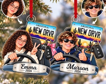 Puede incluir: Dos adornos acrílicos personalizados con un paisaje desértico, una matrícula de Arizona New Drvr y una llave de coche. Un adorno muestra a Emma con el año 2026 y el otro a Marson con 2026, ambos colgados con cintas de color rojo.