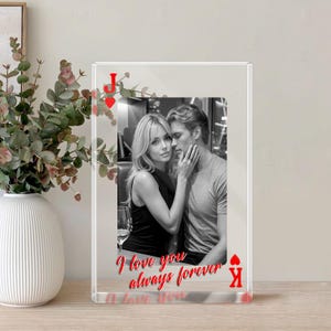 Könnte beinhalten: Transparenter Acryl-Fotoblock mit einem Schwarz-Weiß-Bild eines Paares. Rote Spielkartensymbole und der Text "I love you always forever" sind auf den Block gedruckt. Eine dekorative Vase mit Grünpflanzen befindet sich im Hintergrund.