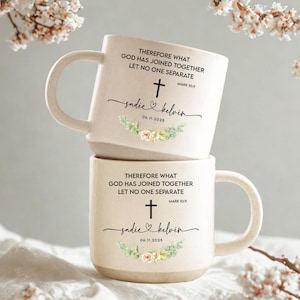 May include: Two stacked cream ceramic mugs. Each mug has the text "THEREFORE WHAT GOD HAS JOINED TOGETHER LET NO ONE SEPARATE" with a cross, the names "sadie & kelvin" and the date "06.11.2025". Floral accents are also present on each mug.
