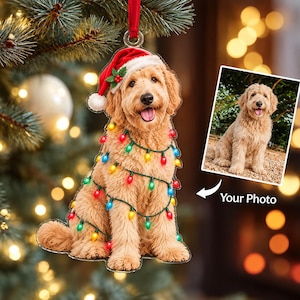 May include: A custom acrylic Christmas ornament shaped like a golden doodle dog wearing a red Santa hat and wrapped in colorful string lights. A small square photo of the same dog is displayed to the right with the text Your Photo below it.