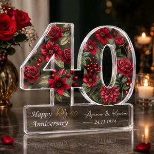 Könnte beinhalten: Transparente Jubiläumsdekoration aus Acryl mit der Zahl 40, gefüllt mit roten Blumenmustern. Die Basis zeigt "Happy Ruby Anniversary" sowie Namen und ein Datum. Ein dekoratives Andenken für einen besonderen Anlass.