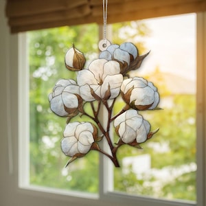 Op de afbeelding: Een decoratief hangornament met een katoenplantontwerp. Het ornament toont witte katoenbloesems met bruine stelen en bladeren. Het hangt aan een zilveren ketting en creëert een op de natuur geïnspireerd accent.