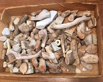 May include: A cardboard box filled with a variety of natural antler pieces in various shapes and sizes. The antler pieces are a light beige color and have a rough, natural texture.