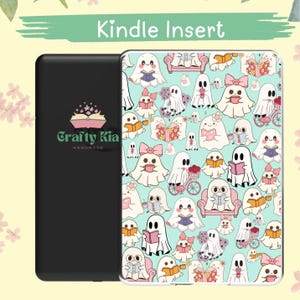 May include: A black Kindle insert with a light blue cover featuring a pattern of cartoon ghosts reading books, with bows, and riding bicycles. The text "Kindle Insert" is at the top. The brand logo "Crafty Kia Handmade" is on the black insert.