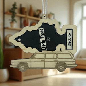 May include: Wooden air freshener with a car graphic and the text "Little Trees" and "Black Ice". The air freshener is shaped like a tree with a black center and a car design at the bottom, hanging from a white string.