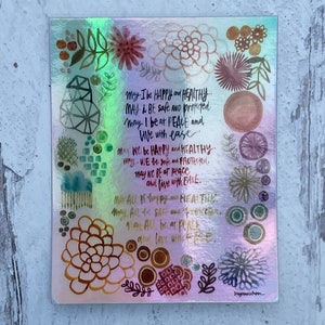 May include: A colorful, iridescent print with a floral design and the text "May I be happy and healthy. May I be safe and protected. May I be at peace and live with ease. May we be happy and healthy. May we be safe and protected. May we be at peace and live with ease. May all be happy and healthy. May all be safe and protected. May all be at peace and live with ease."